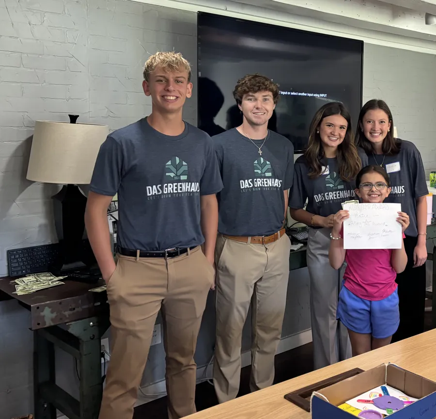 The Das GreenHaus interns with a camper holding up her award